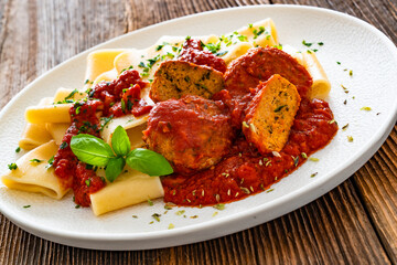 Pasta with meatballs in bolognese sauce on wooden table	