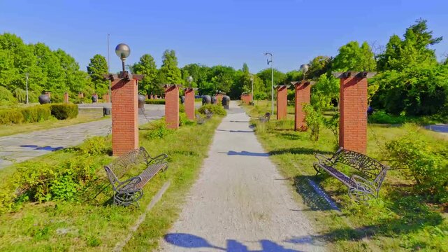 Herastrau Garden in Bucharest, with brick columns and benches. Alley in Herastrau Park. Sunny summer days in Romania. Hot day