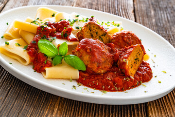Pasta with meatballs in bolognese sauce on wooden table	