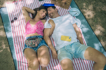 Couple relaxing on picnic blanket by river, enjoying summer day