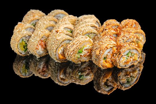 Crispy deep fried sushi rolls with sauce on black background