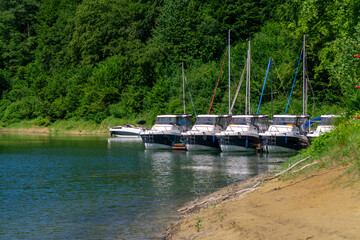Bieszczady Solina Lake, motorboats and sailboats moored by the shore surrounded by green forest,...