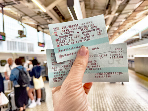 Tokyo, Japan - October 25, 2024: Exploring Tokyo: Holding shinkansen tickets at a busy train station in Japan