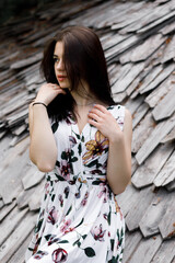 Girl in a floral dress against the background of a wooden roof