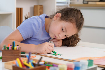 Caucasian preteen girl focusing coloring picture green crayon during elementary classroom art...
