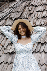 Girl in dress and hat against wooden roof background