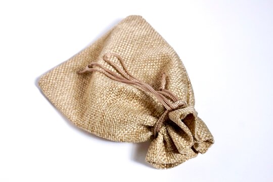 Fasten small burlap brown woven coin pouch object isolated on horizontal white background.