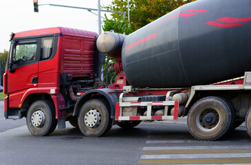 Heavy concrete truck making a turn at an intersection during the late afternoon in an urban setting