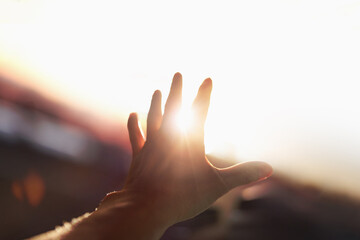 A strong, brilliant beam of light shining through the arms and fingers stretched out toward the...