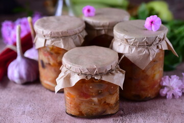 Vegetable salad in jars on a brown background. Home-made preserves. Vegetable salad in jars