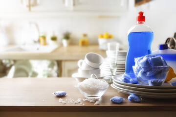 Dishwasher products on table with tableware and background kitchen