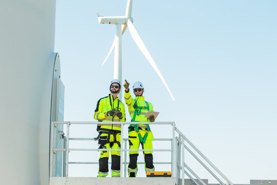 Team of engineers inspecting and planning maintenance at wind turbine power site.