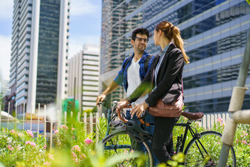Asian man with female friend cycling, commuting to work for health and eco lifestyle.