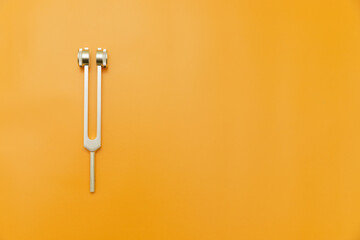 tuning fork on Orange Background, Space for Text, Space for Logo, medical instrument, medical equipment,