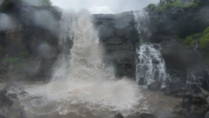 Majestic Waterfall Cascading through Lush Green Hills and Rocks