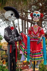 Fototapeta premium Dia de los Muertos (Day of the Dead) skeletons and sugar skulls, funny catrinas with clothes, Halloween decor in Old Town San Diego, California