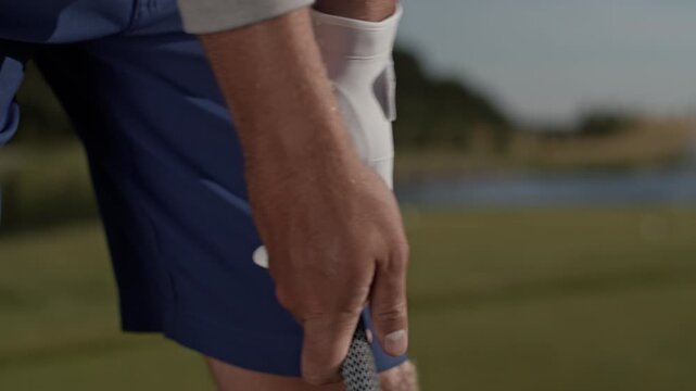 Man golfer with glove holds golf club preparing for swing