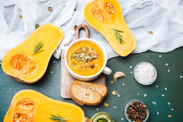 Butternut squash soup with pumpkin seeds garnished with rosemary and croutons on a table