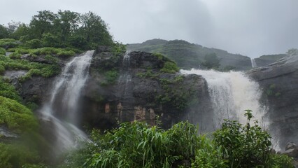 Majestic Waterfall Cascading through Lush Green Hills and Rocks