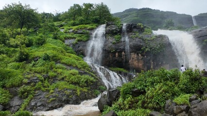 Majestic Waterfall Cascading through Lush Green Hills and Rocks