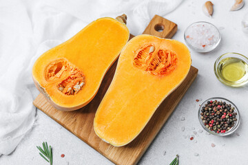 Whole butternut squash cut in half, seeds visible, arranged with salt, oil, peppercorns, and herbs...