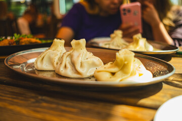 Delicious khinkali traditional Georgian dumplings filled with meat are beautifully arranged on a metal platter garnished with spices in a warm dining setting