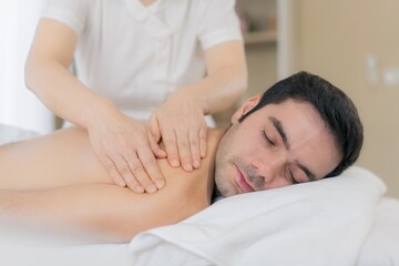 Asian male receiving back massage therapy at spa for relaxation, burnout recovery, and self-care.