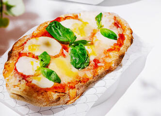 Delicious margherita flatbread served on a white background with basil