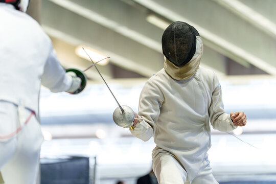 Athletes fencing in protective gear during modern pentathlon event with &eacute;p&eacute;e