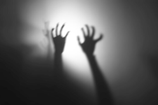 silhouette of hands in spotlight,Shadow overlay effect for halloween background with Terrifying scary hands with long nails,Creepy monster claw,silhouette of hands,zombie hand rising out of a graveyar