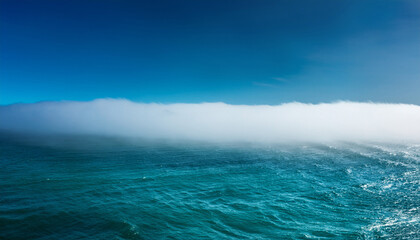 Fototapeta premium rolling white fog bank over a teal ocean horizon