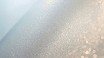 A soft, textured background with a diagonal gradient from a light blueish-grey to a shimmering, bokeh-filled pale gold.