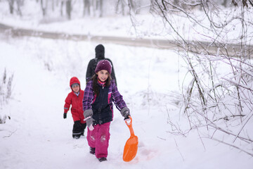 Family walking in snowy woods pulling sled on winter day