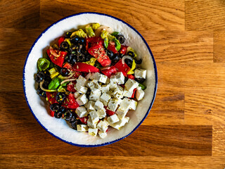 Greek style salad - fresh tomatoes with feta cheese and black olives on wooden table	