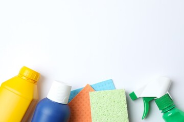 Flat lay with cleaning supplies including bottle, sponge, spray on white background. Top view