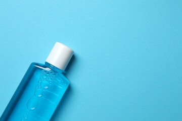 Mouthwash bottle for oral hygiene on blue background. Rinsing mouth with liquids helps against bad breath, cavities and plaques. Dental care product. Copy space.