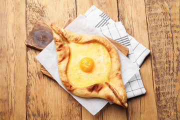 Tasty khachapuri with cheese and egg on wooden table, top view
