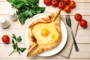 Tasty khachapuri with cheese and egg served on wooden table, flat lay