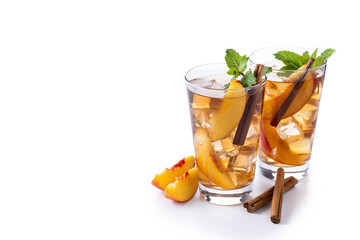 Refreshing peach iced tea in glass with ice cubes and cinnamon isolated on white background. Copy space