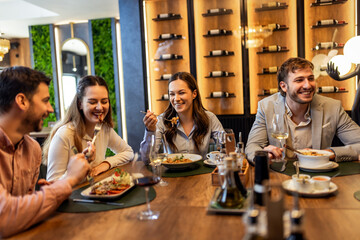 Colleagues Eating and Talking Over Lunch with Wine at RestaurantColleagues Eating and Talking Over Lunch with Wine at Restaurant