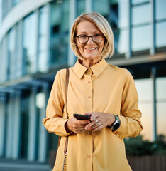 Businesswoman talking on phone with suitcase outdoors