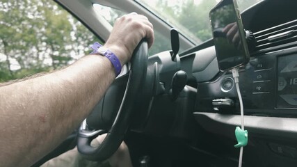 Close-up shot of a man's hands turning a steering wheel while driving.