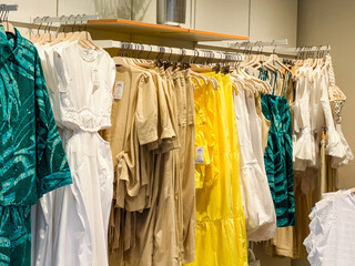 Clothing collection displayed on hangers in boutique shop with seasonal fashion dresses and...
