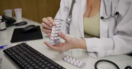Close-up of female doctor holding medication blister pack while explaining prescription details...