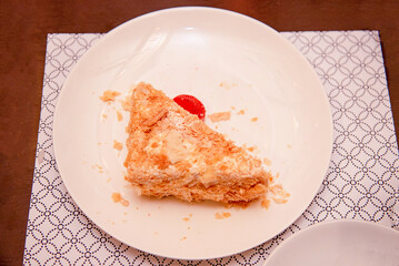 Piece of baking sweet pie cake Napoleon on white plate on table in restaurant