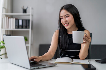 woman is sitting at a desk with a laptop and a mug of coffee