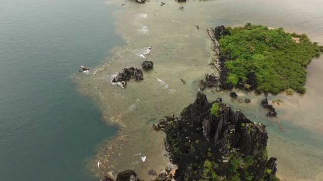 Drone perspective above Poule de Hienghene rock formation and coral reef surrounded by emerald waters in New Caledonia.