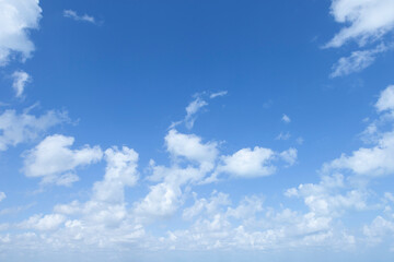 A brilliant blue sky is dotted with fluffy, white cumulus clouds on a perfect, clear day.