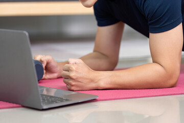 Naklejka premium Home Fitness. Young man doing plank exercise with laptop for online workout.