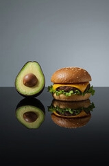 Healthy vs Unhealthy Food Choice, Fresh Avocado Half vs Cheeseburger on Black Reflective Surface, Diet and Wellness Concept